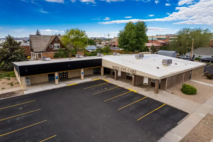 Single-story commercial building with a paved parking lot, brown brick facade, and light-colored roofing