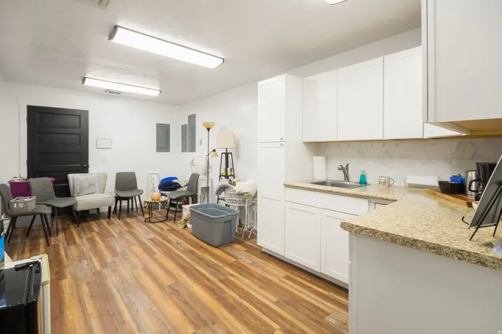 Open-concept kitchen and living area featuring white cabinetry with wood-finish countertops, stainless steel appliances, wood-finish flooring throughout, and recessed ceiling lighting