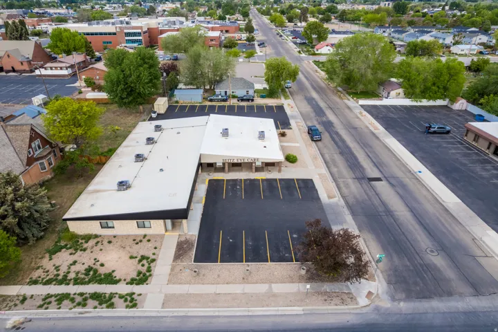 Commercial property featuring an asphalt parking lot with marked spaces, a flat roof, and multiple exterior windows