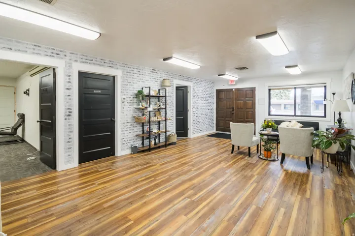 Wood-finish flooring, white brick-style accent walls, recessed lighting, and a double entry door with paneled wood finish
