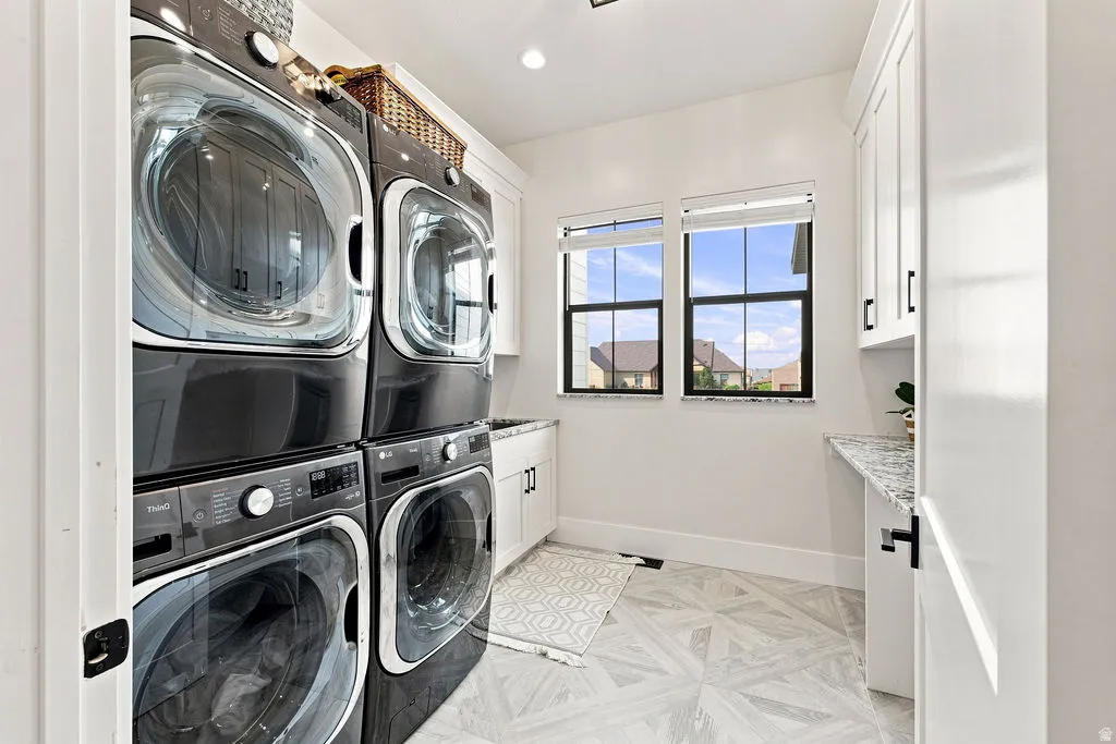 Dual stacked laundry appliances complemented by white cabinetry and a speckled countertop