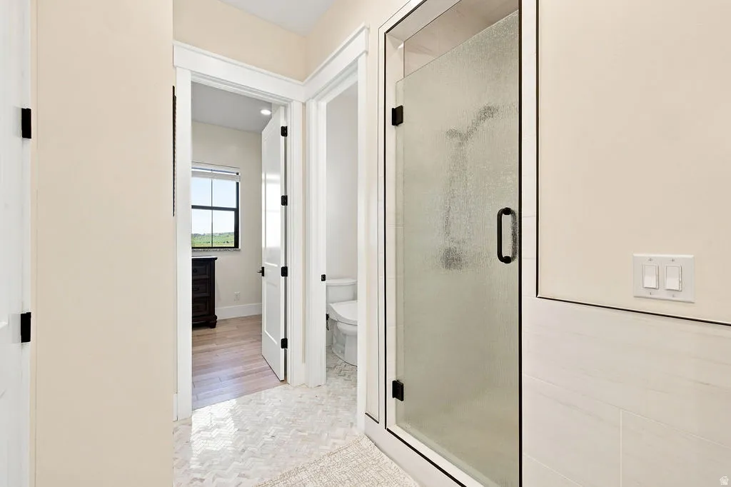 Frosted glass shower enclosure with matte black hardware, white rectangular wall tiles, and hexagon-patterned floor tiles