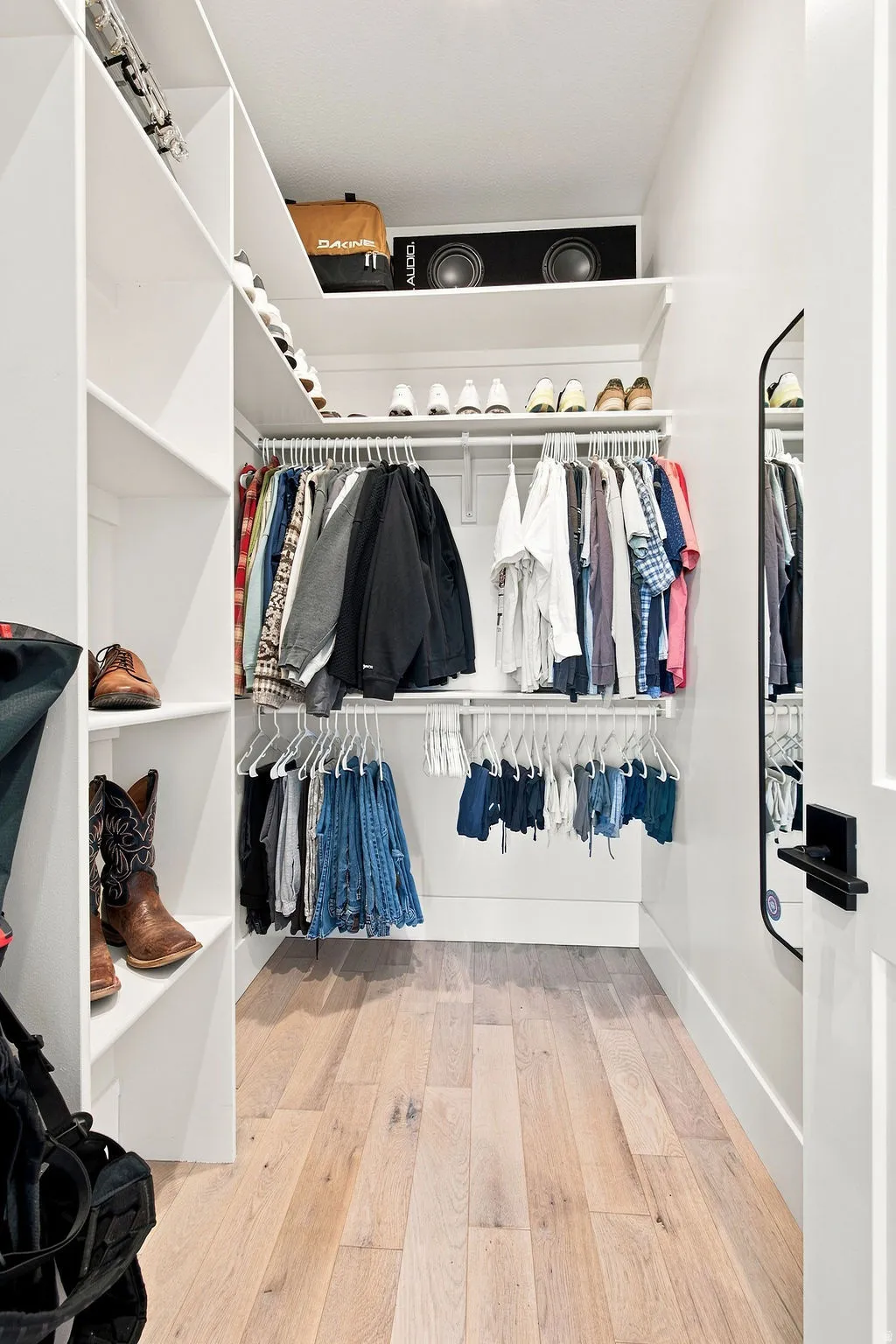 Walk-in closet featuring built-in shelving, multiple hanging rods, and wood-finish flooring