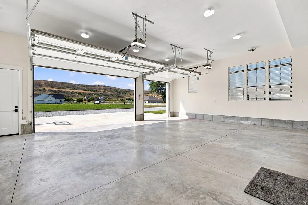 Spacious garage with multiple windows, concrete flooring, and an automatic garage door opener
