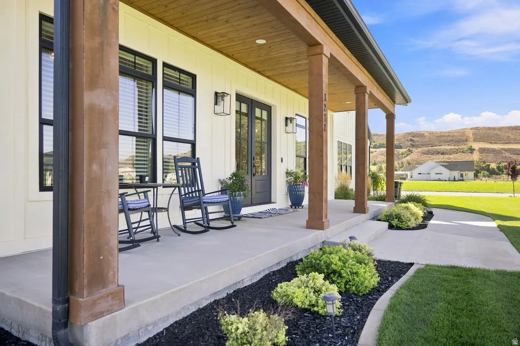 Expansive covered front porch with wood-clad columns, board-and-batten siding, and dark-framed windows