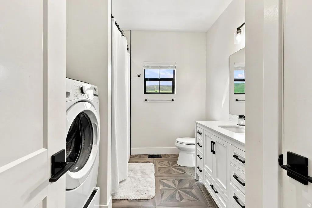 White vanity with a single basin, dark hardware, and a framed mirror