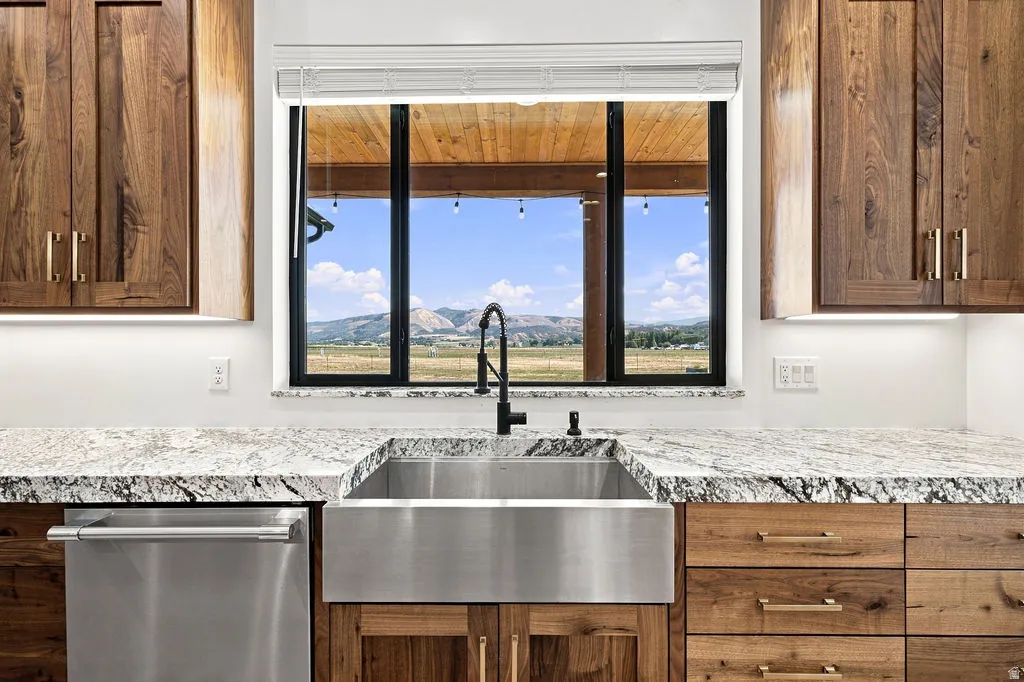 Stainless steel apron-front sink with a matte black gooseneck faucet, set within granite countertops