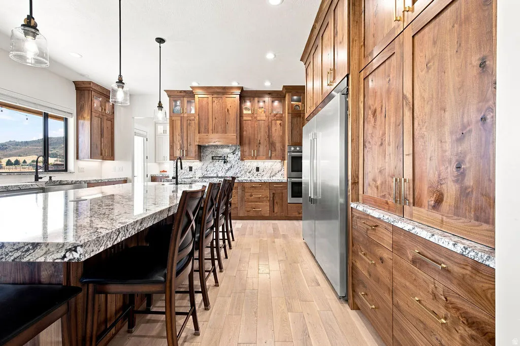 Gourmet kitchen featuring extensive wood cabinetry, light wood-finish flooring, a large island with a stone countertop, and stainless steel appliances