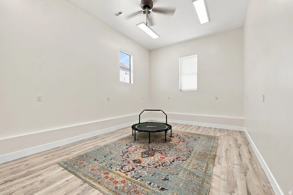 Wood-finish flooring, white walls, and a ceiling fan with integrated lighting