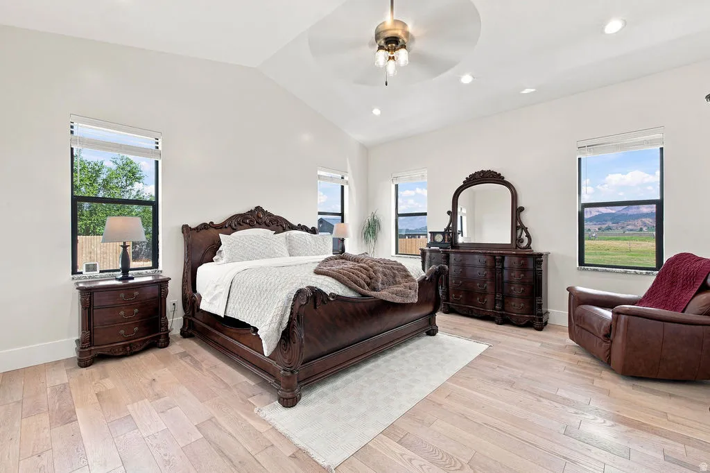 Vaulted ceiling with recessed lighting and a ceiling fan, light wood-finish flooring, and multiple windows