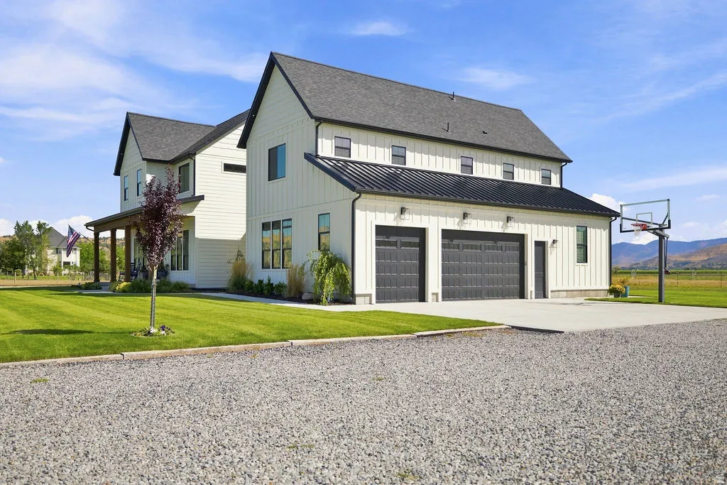 Modern farmhouse architecture featuring board and batten siding, a two-car garage with dark paneled doors, and a covered porch with wood columns