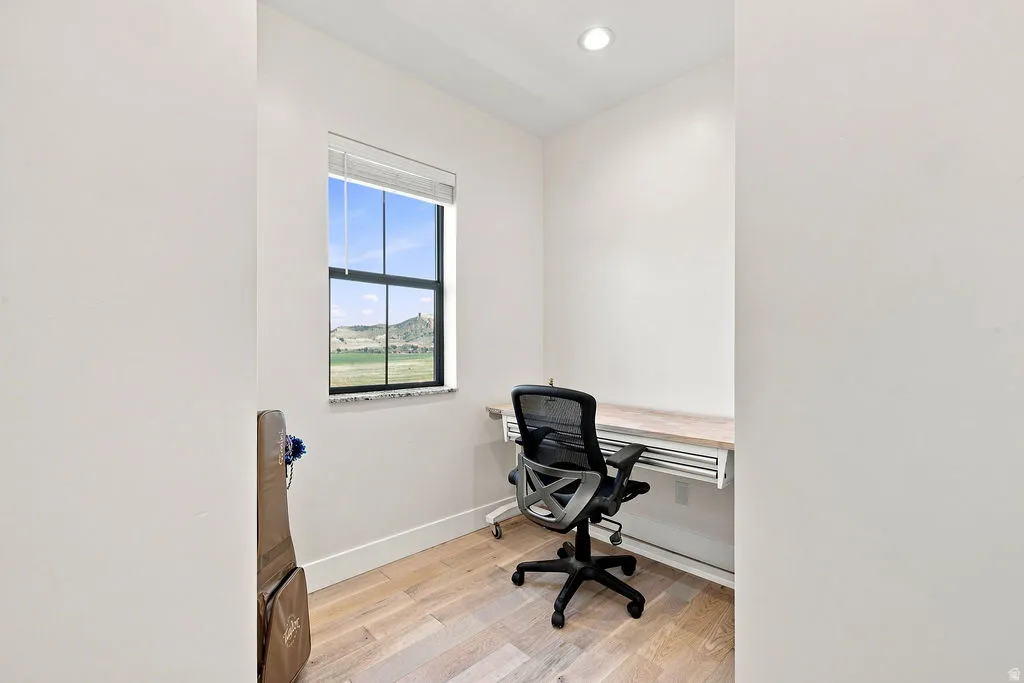 Recessed lighting, light wood-finish flooring, built-in desk, and a window with exterior scenery