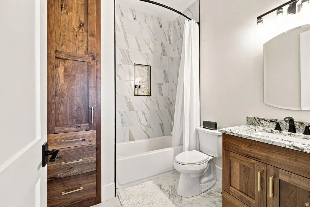 Bathroom featuring a tub with tile surround, wood-finish vanity with stone countertop, and wood-finish storage cabinetry