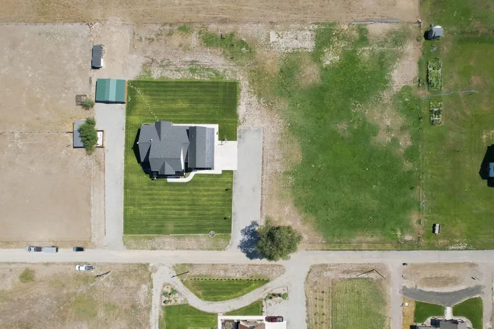 Property featuring a main residence, detached outbuilding, expansive grassy area, and paved driveway