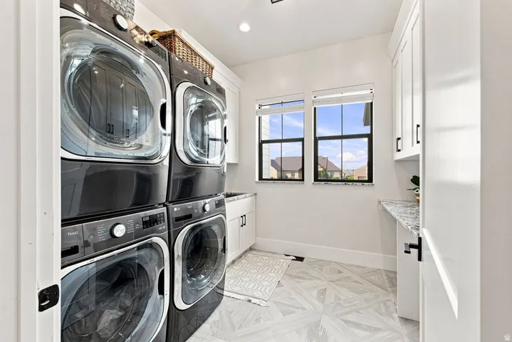 Dual stacked laundry appliances complemented by white cabinetry and a speckled countertop