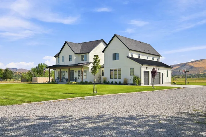 Modern farmhouse exterior with white vertical siding, black-framed windows, and a covered front porch featuring wood columns