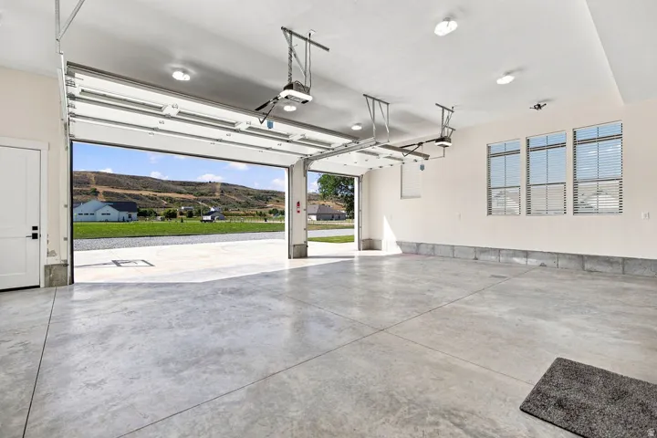 Spacious garage with multiple windows, concrete flooring, and an automatic garage door opener