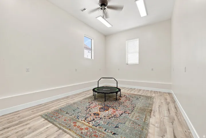 Wood-finish flooring, white walls, and a ceiling fan with integrated lighting