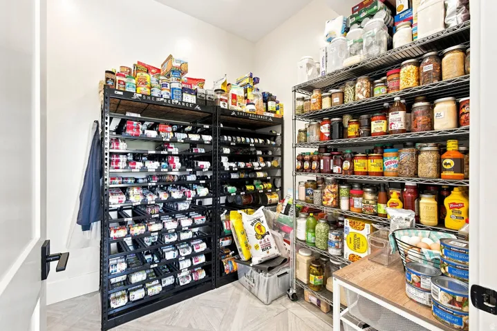 Spacious pantry featuring multiple shelving units, light-colored walls, and tile flooring
