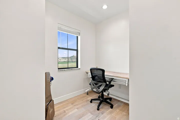 Recessed lighting, light wood-finish flooring, built-in desk, and a window with exterior scenery