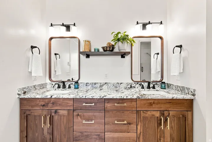 Dual wood-finish vanity with granite-style countertop and integrated sinks, complemented by matte black hardware