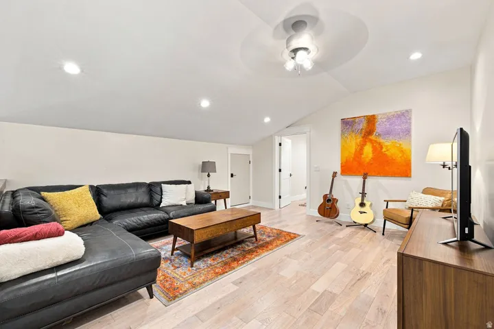 Vaulted ceiling with a ceiling fan, recessed lighting, wood-finish flooring, and a white interior door