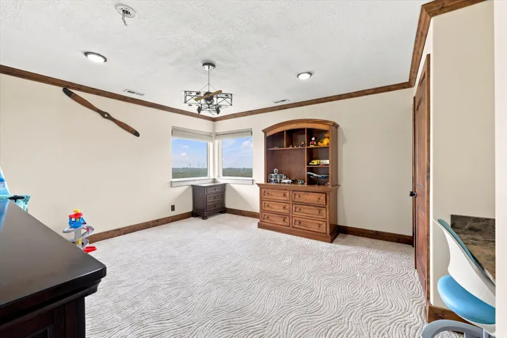Room featuring textured carpet flooring, wood-toned trim, recessed lighting, and a corner window arrangement