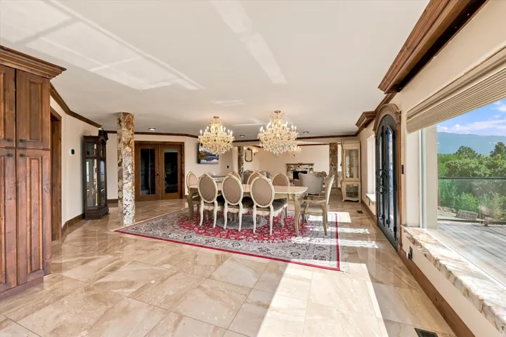 Porcelain tile flooring, two crystal chandeliers, decorative stone column, and a large window with a marble-look sill