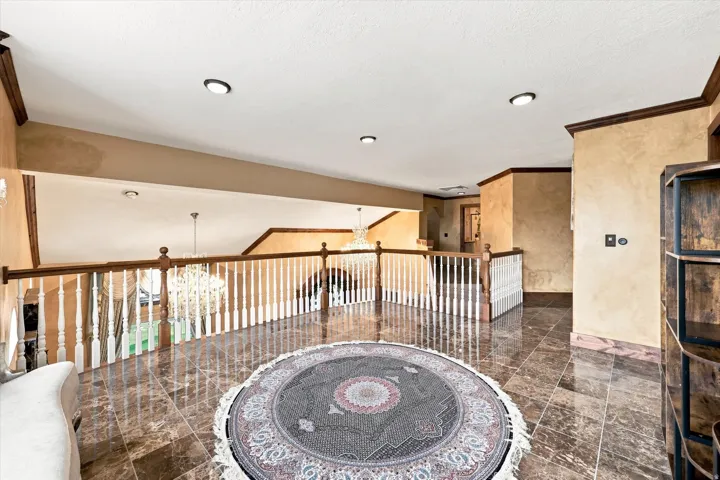 Upper-level landing featuring polished tile flooring, wood handrails, and white balusters