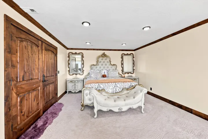 Wood-paneled double doors, recessed lighting, crown molding, and light-colored carpeting