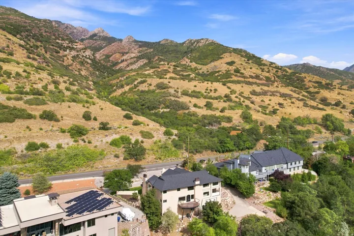 Mountainous backdrop, terraced landscaping, multi-level residences, solar panel installation, paved driveway