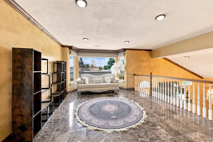 Recessed lighting, bay window, tile flooring, painted railing, and wood-finish handrail