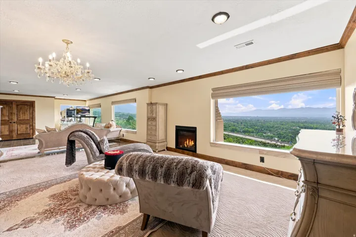 Expansive room featuring multiple windows, a crystal chandelier, recessed lighting, a built-in fireplace, and wood trim