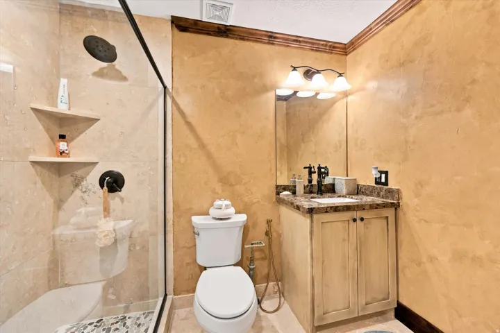 Glass-enclosed shower with tiled walls and pebble flooring