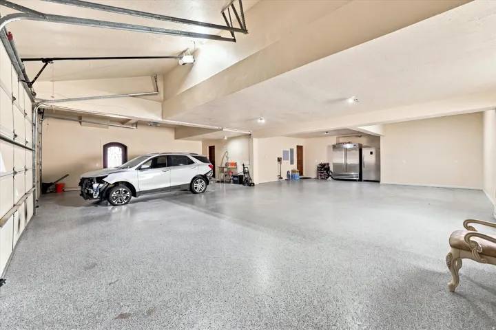 Spacious garage featuring a durable epoxy floor, recessed lighting, and multiple industrial-style refrigerators