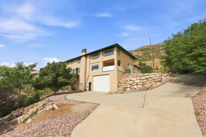 Multi-level residence featuring a stucco exterior, integrated garage, and multiple balconies with metal railings