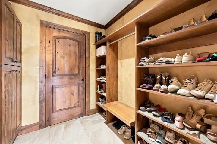 Built-in wood shelving, custom wood cabinetry, wood trim, arched wood panel door, and tile flooring