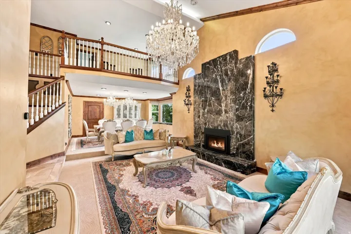 Two-story ceiling height, intricate crystal chandeliers, multi-level living spaces, stone fireplace with hearth, and arched upper windows
