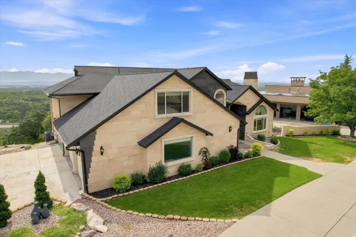 Multi-level residence featuring a stone-clad exterior, dark-toned roof, arched and rectangular windows, and a concrete driveway