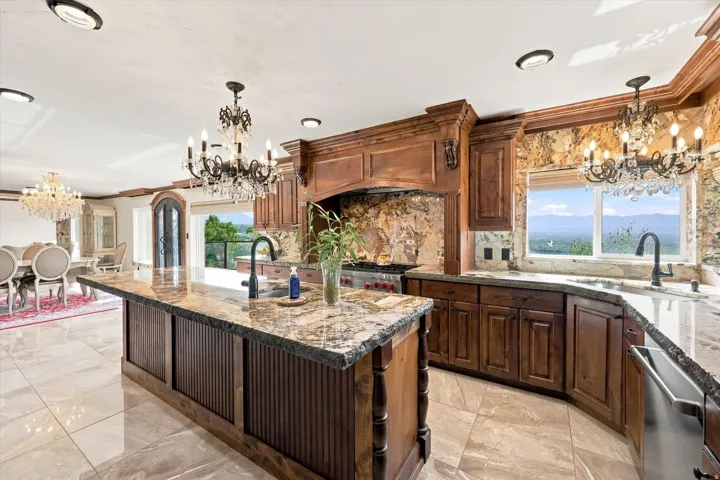 Gourmet kitchen featuring a large central island, rich wood cabinetry, stone countertops, and integrated stainless steel appliances