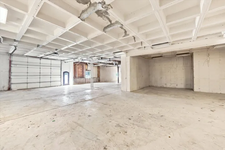 Expansive concrete flooring with a coffered ceiling and fluorescent lighting
