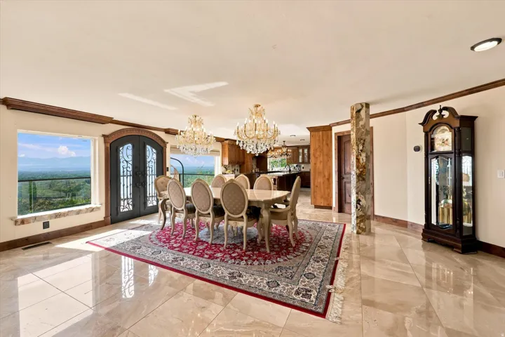 Polished stone tile flooring, decorative wrought iron double doors, two crystal chandeliers, and substantial wood trim accents
