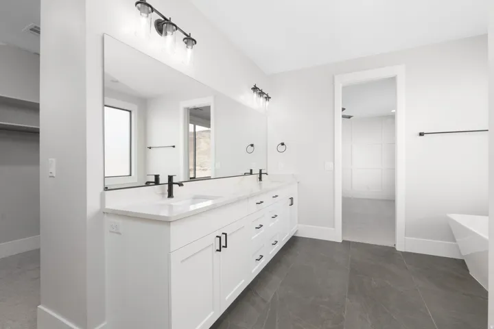 Dual vanity with white cabinetry, matte black hardware, and a single basin sink