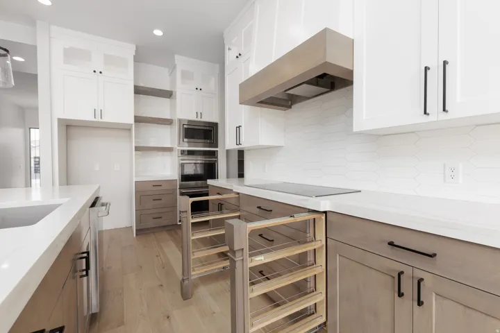 Modern kitchen featuring white shaker cabinetry, light wood-finish flooring, stainless steel built-in appliances, a custom range hood, and light-toned countertops