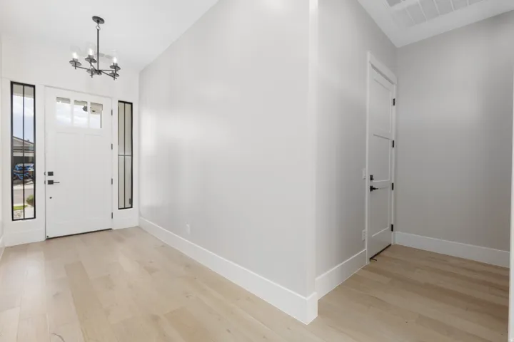 Entryway featuring light wood-finish flooring, a white paneled front door with clear glass inserts, and black framed sidelights