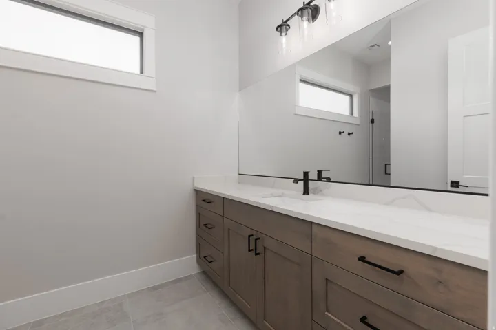 Modern vanity with wood-finish cabinetry, white stone countertop, and integrated rectangular sink