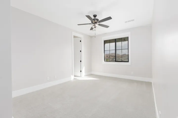 Plush carpeting, a modern ceiling fan, and a transom window with black framing