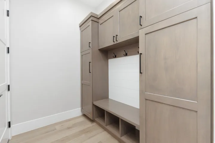Built-in cabinetry with a light wood-finish and black hardware, integrated bench seating, and dedicated storage cubbies