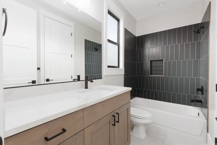Wood-finish vanity with a white countertop, undermount sink, and matte black fixtures