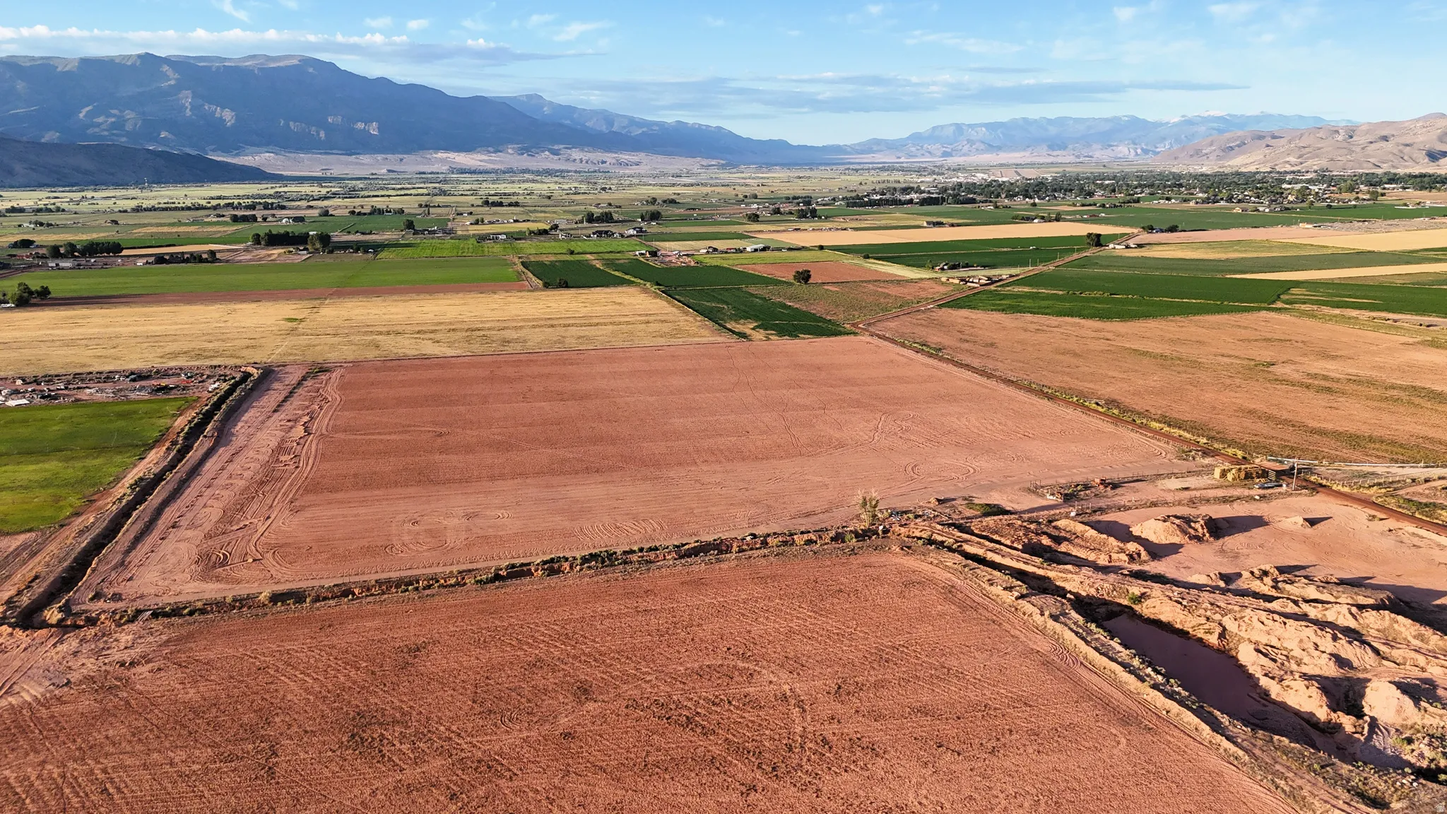 Expansive red earth terrain with cultivated fields and distant mountain ranges